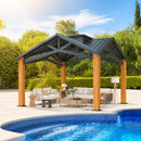 A large outdoor patio gazebo with a dark gray metal roof and light wood posts, furnished with a white sofa, coffee table, and side lamp, situated next to a blue swimming pool with a green garden background.